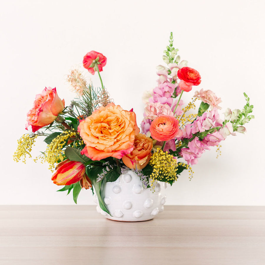 large flower arrangement with orange pink and yellow flowers on table