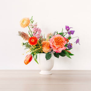 medium flower arrangement with orange pink and yellow flowers on table