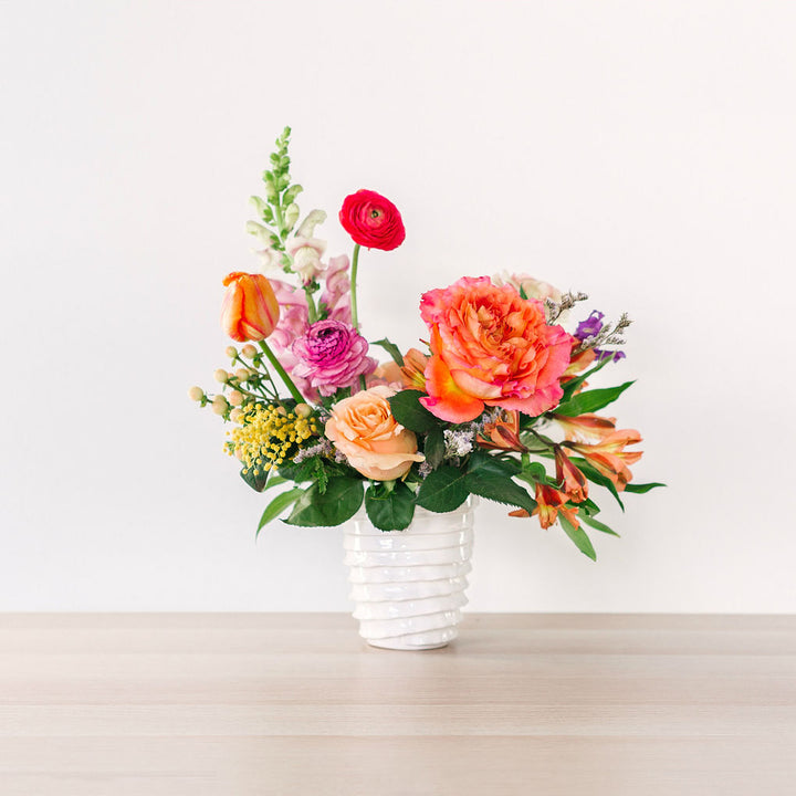 small flower arrangement with orange pink and yellow flowers on table