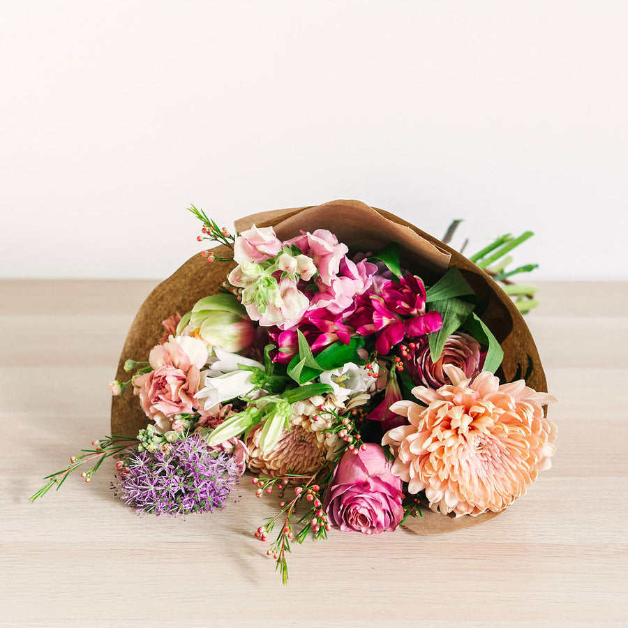 large flower bouquet laying on table with pink orange and purple wildflowers