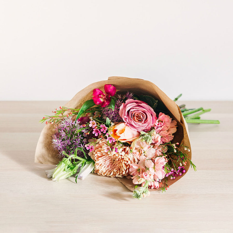 medium flower bouquet laying on table with pink orange and purple wildflowers