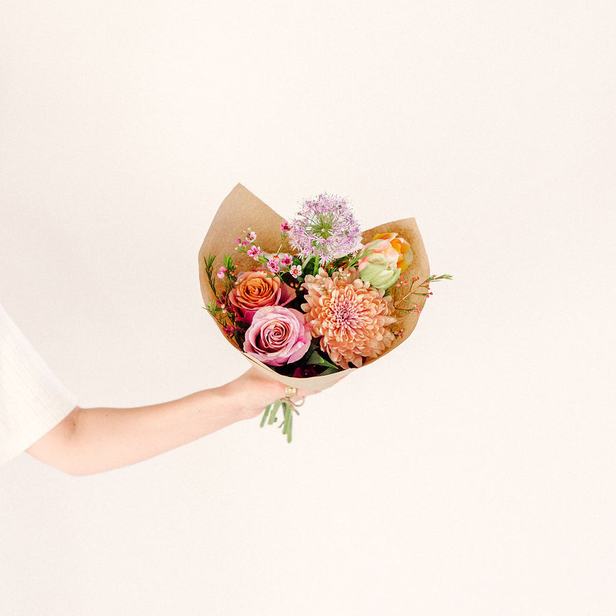 small flower bouquet in outstretched hand with pink orange and purple wildflowers