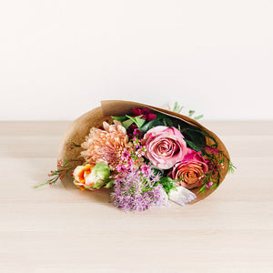 small flower bouquet laying on table with pink orange and purple wildflowers