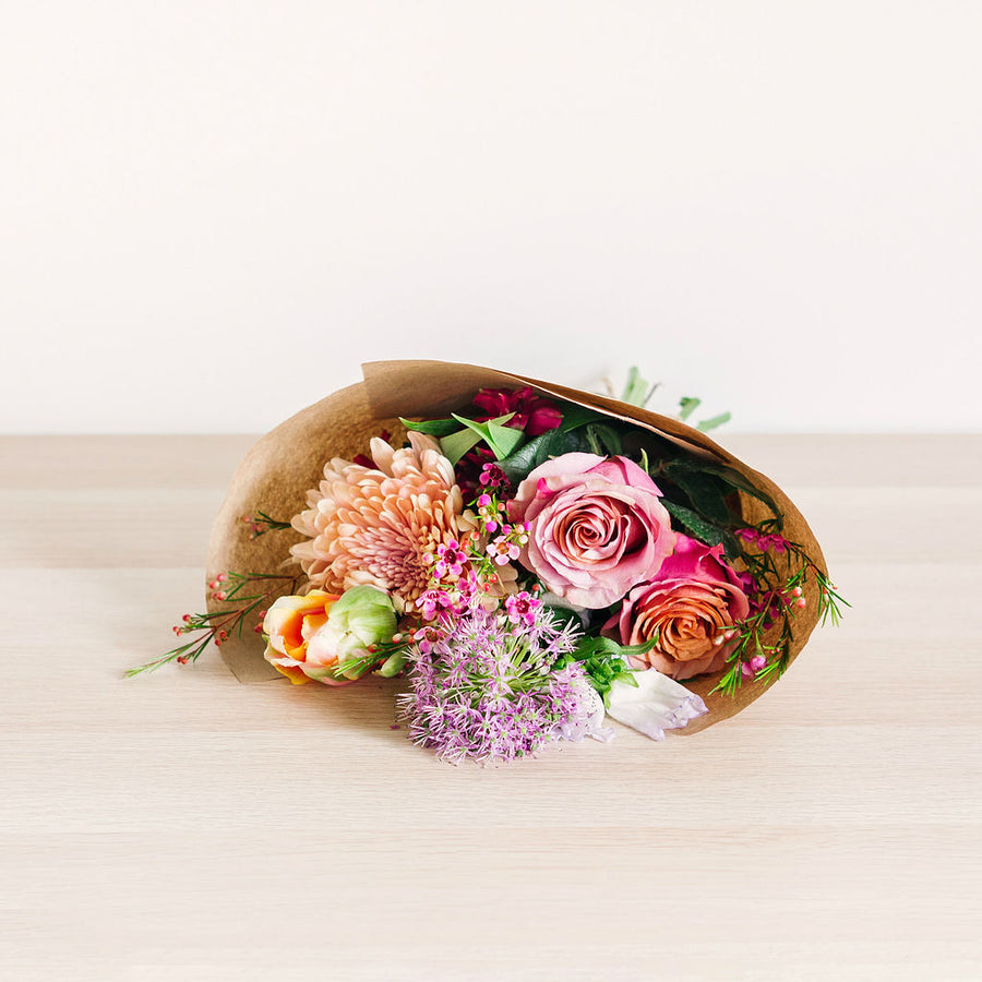 small flower bouquet laying on table with pink orange and purple wildflowers